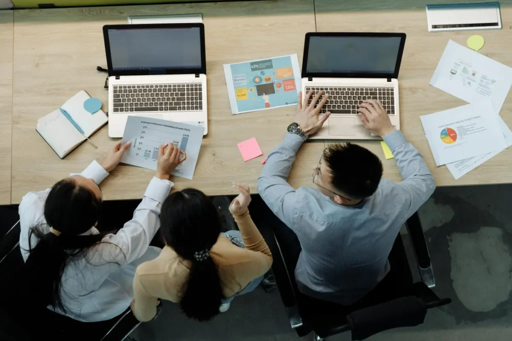 Tiga rekan kerja berdiskusi dan mencari solusi bersama di meja kantor