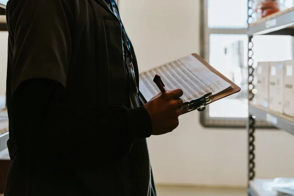 Pekerja gudang memeriksa stok barang dengan clipboard dan checklist